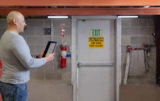 Man using fire safety technology to conduct fire door inspections