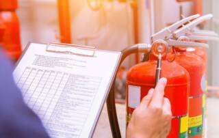Building a Fire and Life Safety Program - showing a worker with a clipboard, procedures, and fire extinguisher