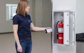 Woman checking fire extinguisher - fire safety tips