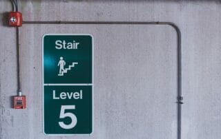 wall with stairs sign next to a fire alarm - importance of fire safety software in workplaces